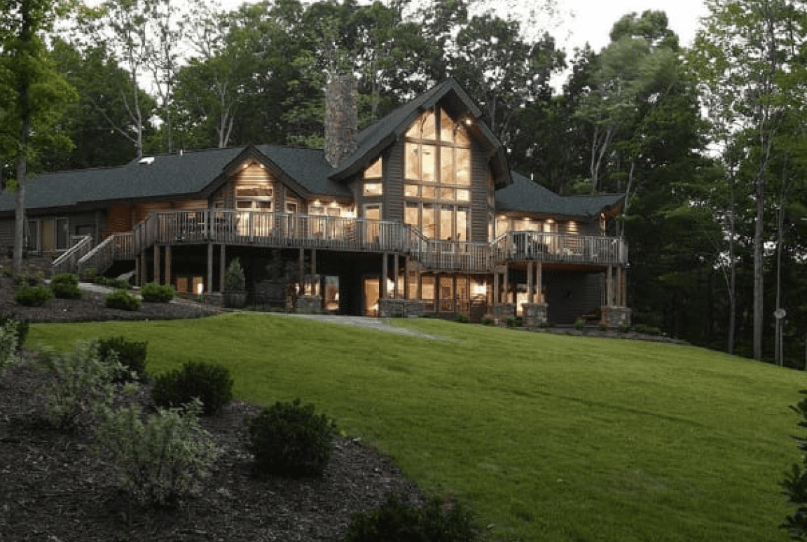 Frame 2095584749 Large cabin-style house surrounded by trees.