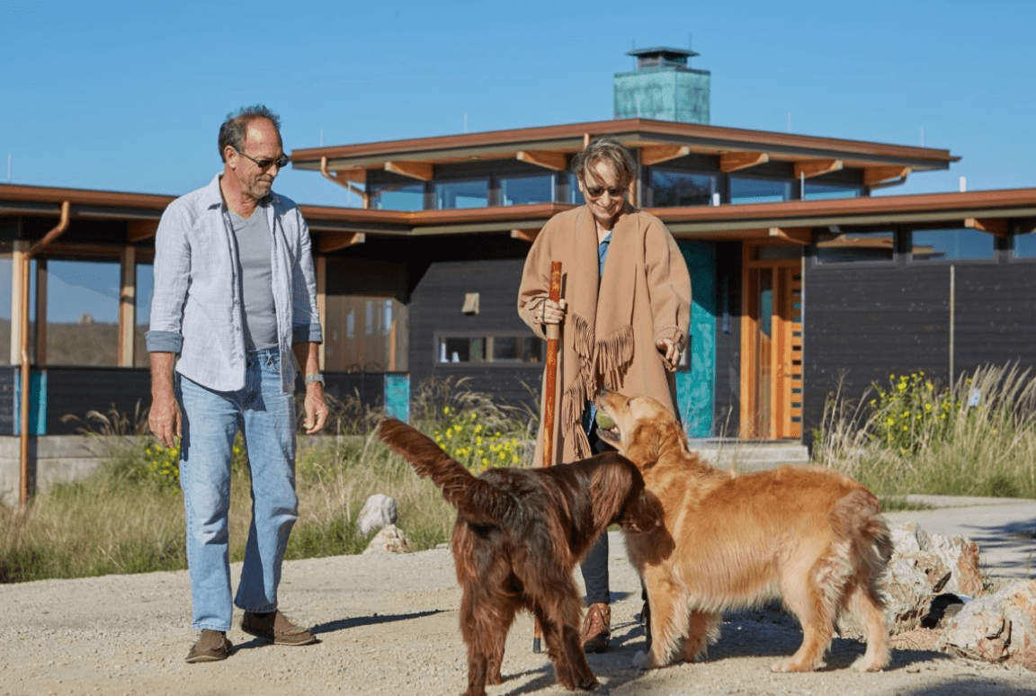 Frame 2095584750 Couple with two dogs outside modern house.