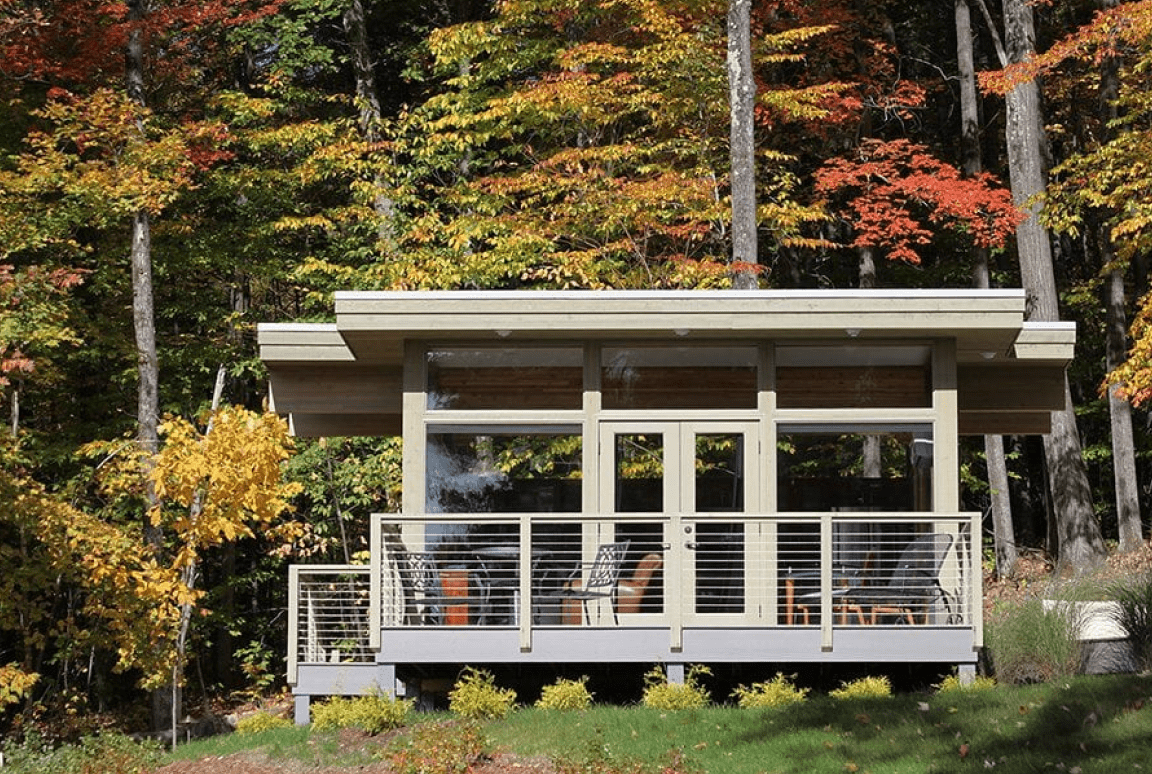Frame 2095584751 Modern cabin surrounded by colorful autumn trees.