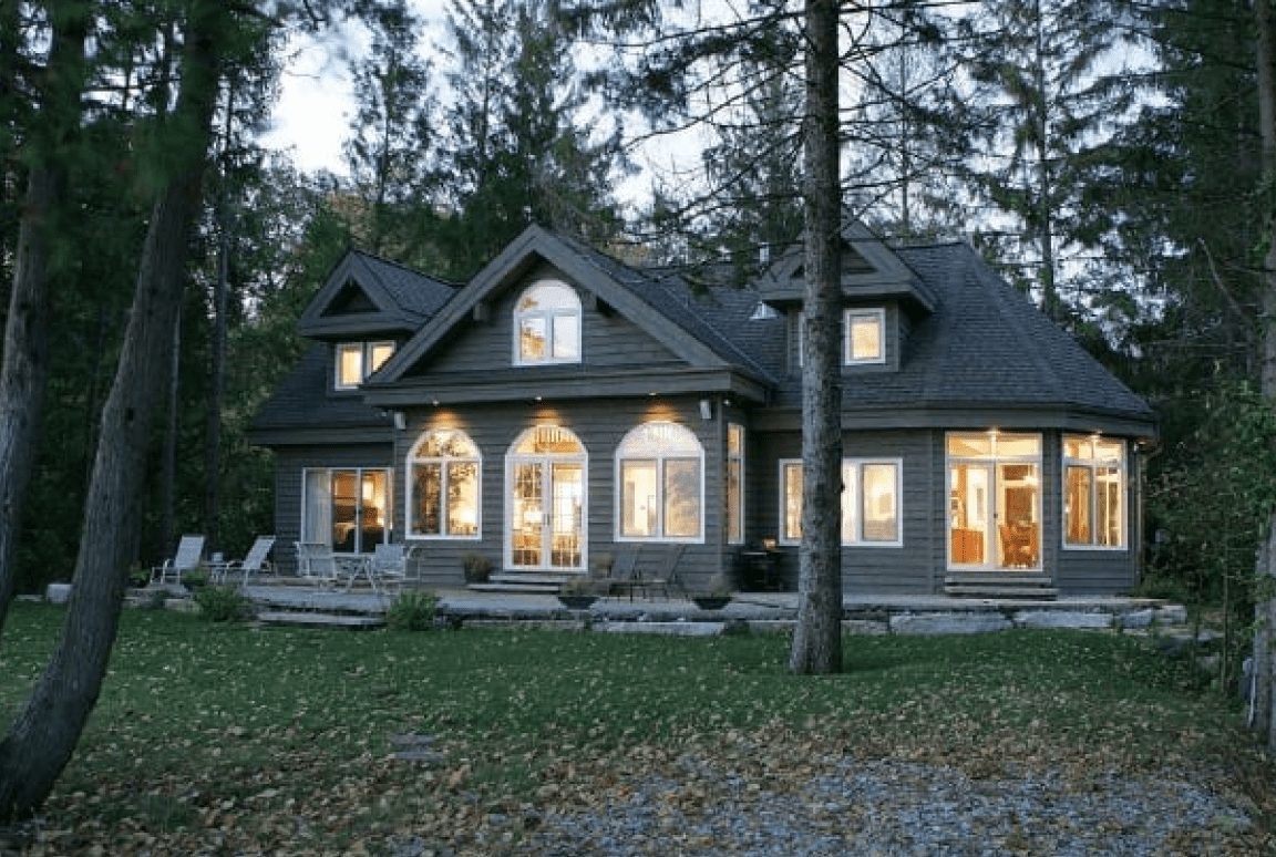 Frame 2095584752 House with illuminated windows in forest setting.